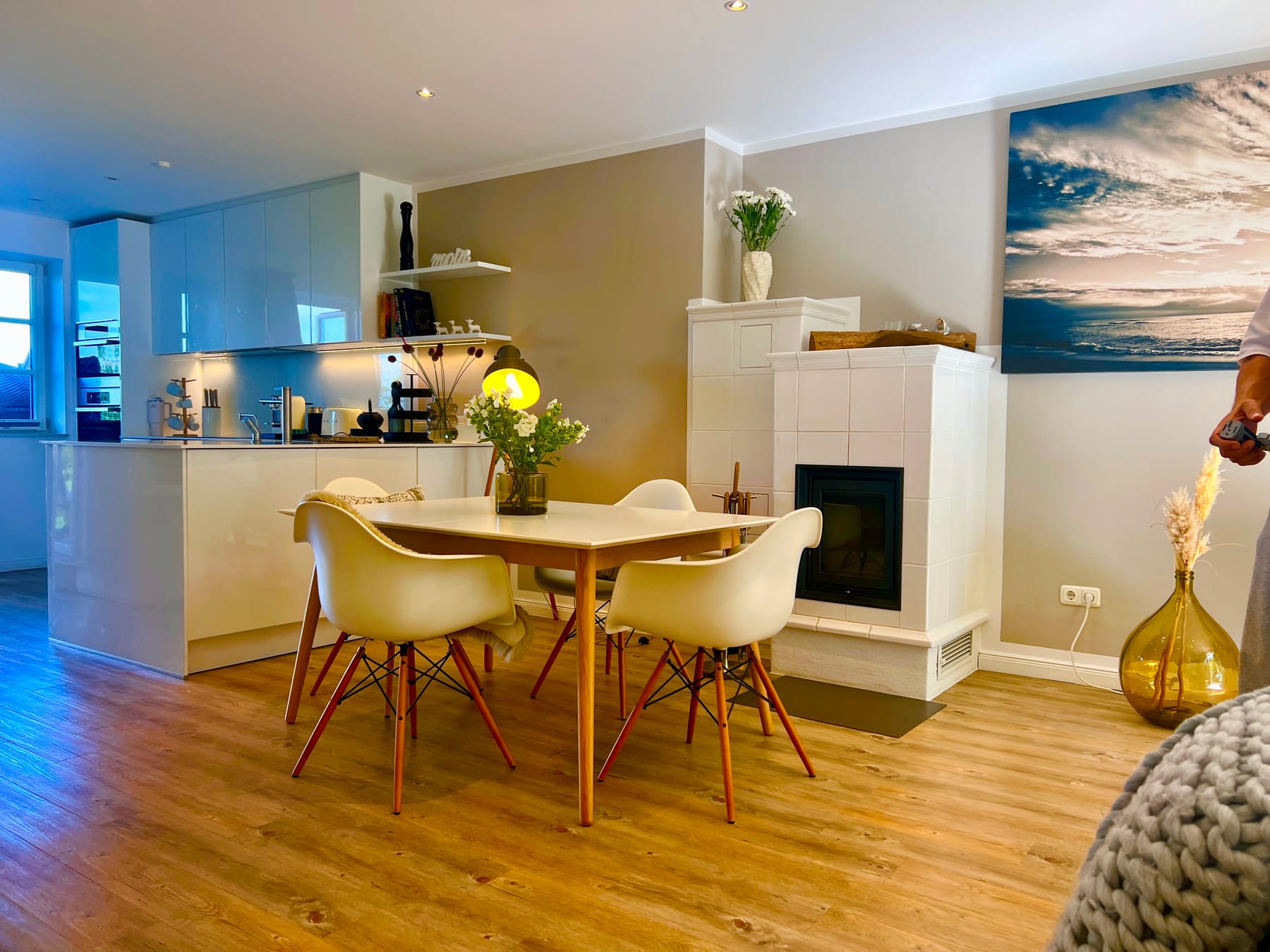 Wohn- und Essbereich mit weißem Kaminofen und Designstühlen