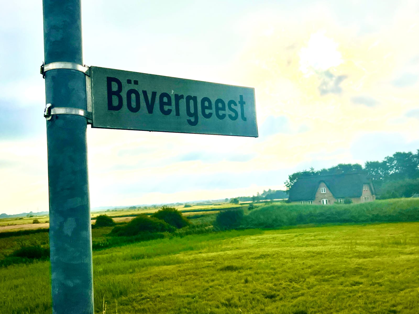Straßenschild Bövergeest mit dem Reetdach-Haus in den Feldern
